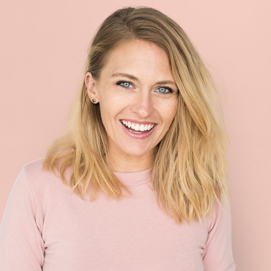 Smiling woman in pink top sitting indoors with natural light background