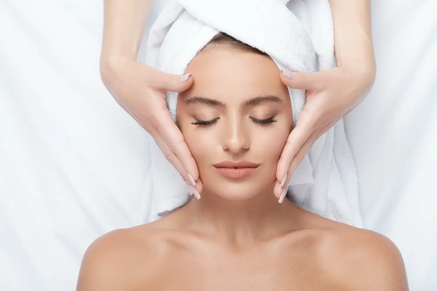 woman receiving relaxing facial massage with eyes closed in spa setting