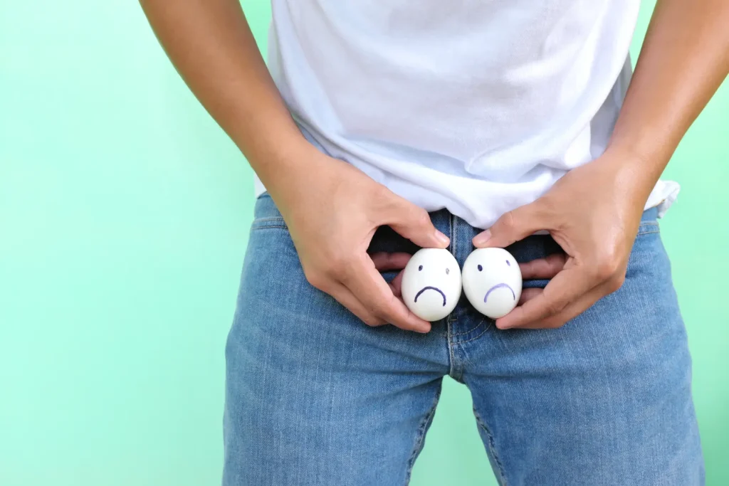 Person holding two eggs with drawn sad faces near the waistband of jeans
